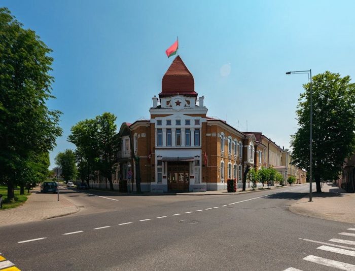 An empty street featuring a historic building with a red flag under a clear sky.