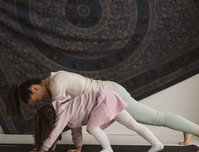 A mother and child practicing yoga together indoors, showcasing family bonding and wellness.
