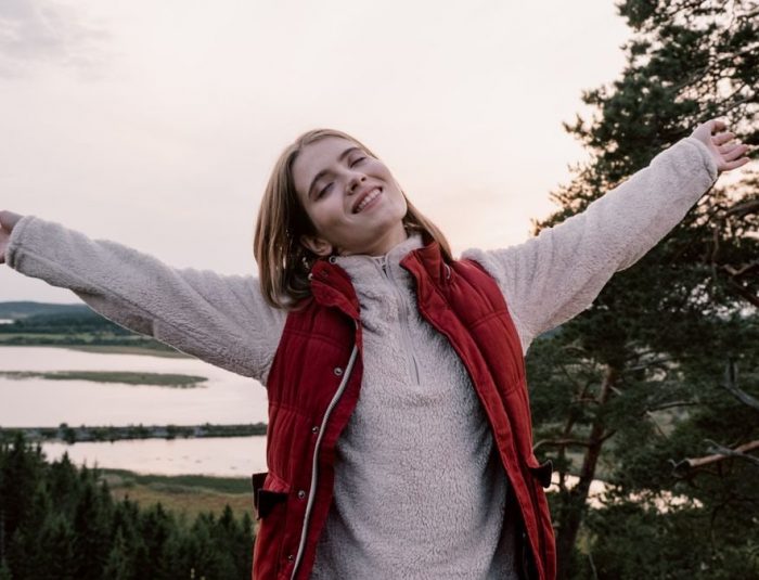 Woman enjoying freedom in a scenic landscape with open arms.