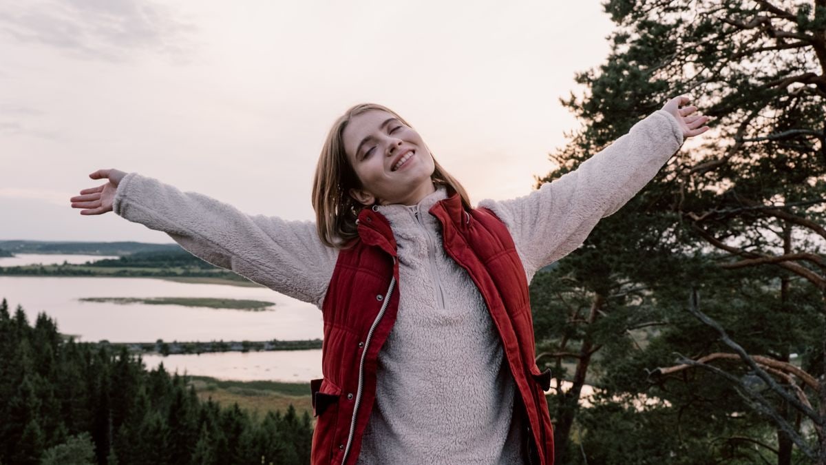 Woman enjoying freedom in a scenic landscape with open arms.